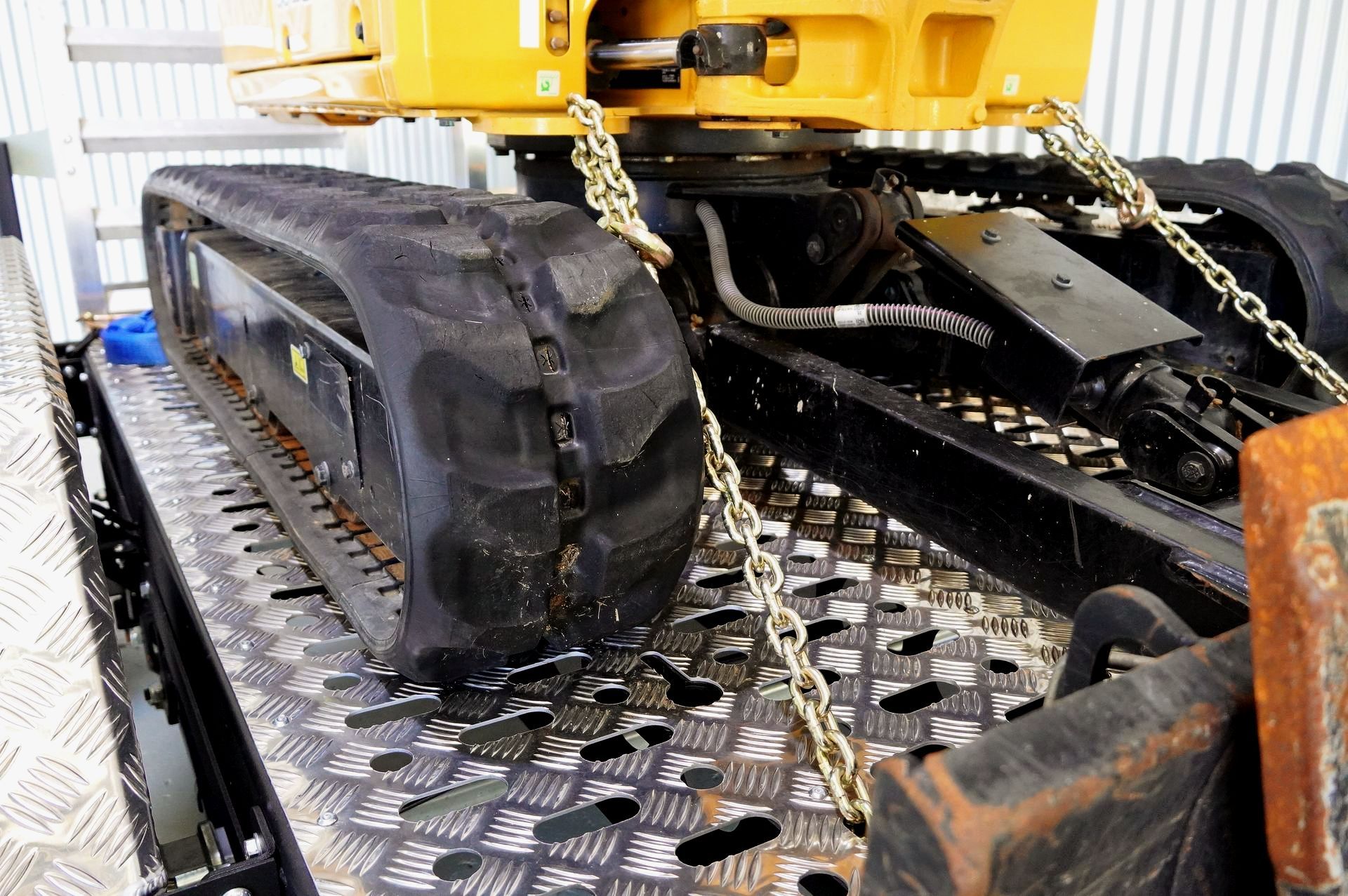 Plant trailer at farm with excavator attachment resting on drawbar. Ox Trailer branding is shown.