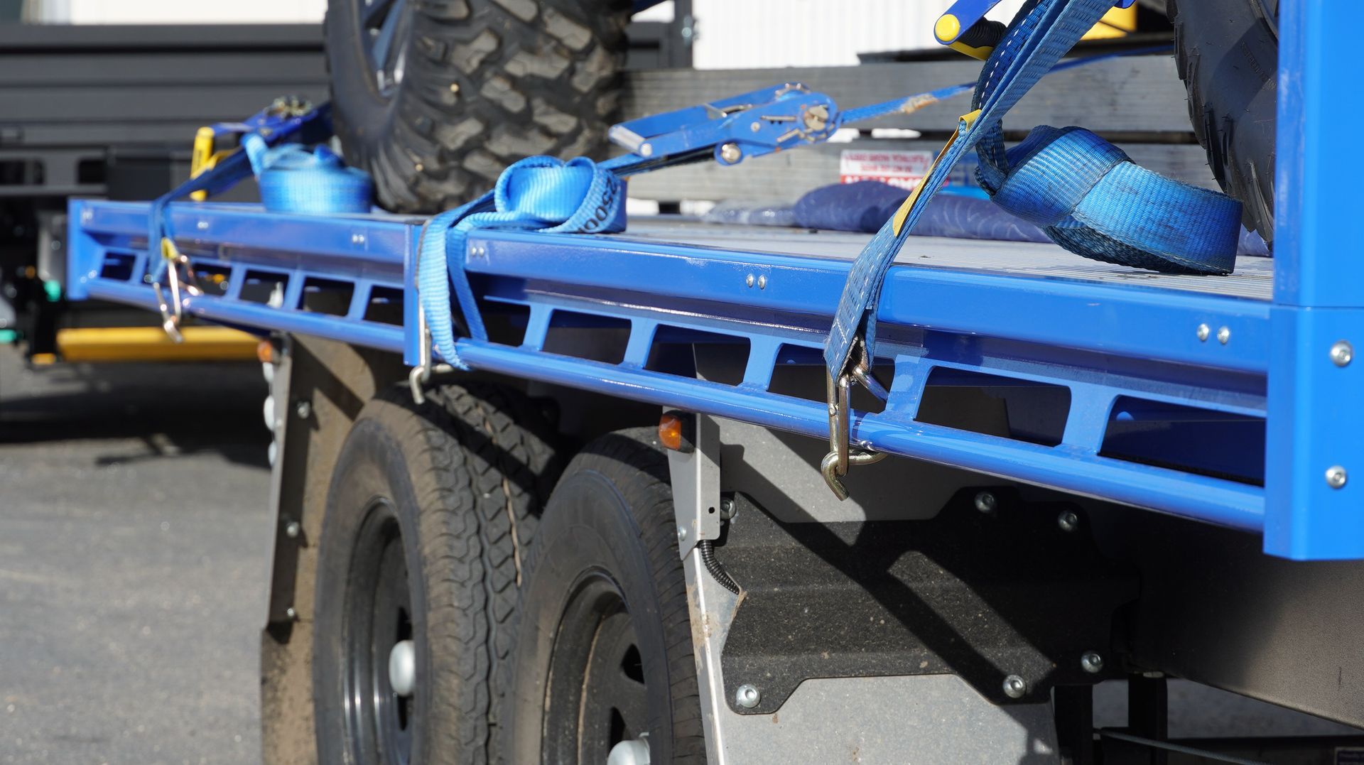 Side rope rail of ox 3.5t trade series flat top trailer with straps stabilising a CFmoto offroad vehicle.