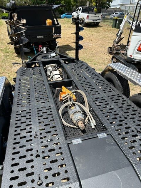 The auger of an excavator in the auger storage of an ox trailer