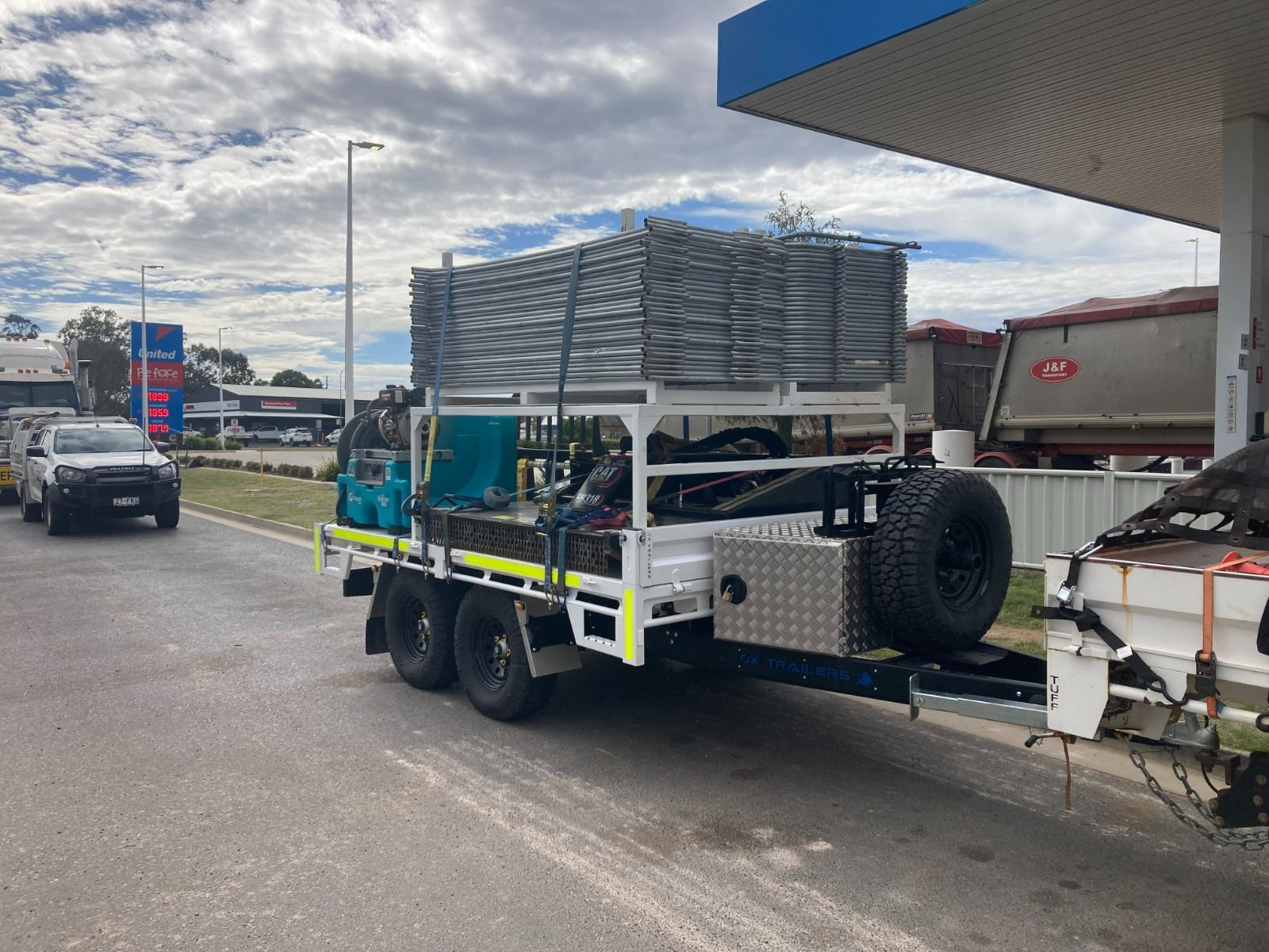 The front-side view of the monster hire flat top trailer as it is loaded with machinery and framing.
