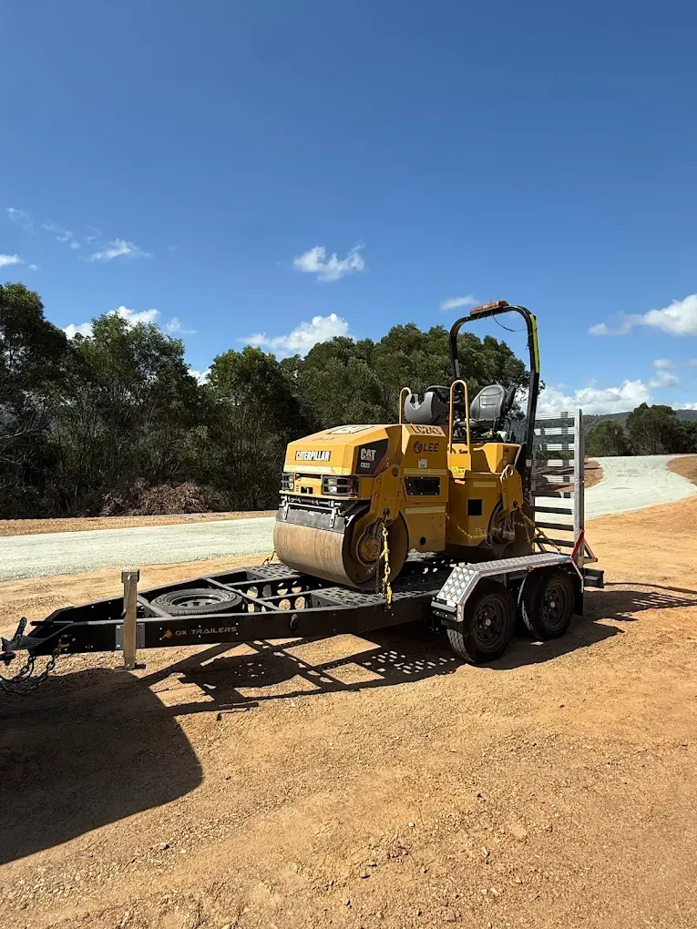 heavy duty custom flat top trailer for gee building at rural construction site with toolbox and canopy doors open.