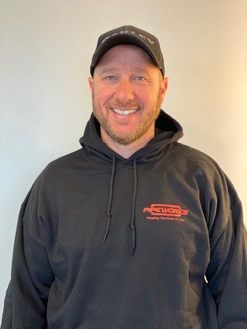 Man wearing a black hoodie and cap, smiling at the camera.