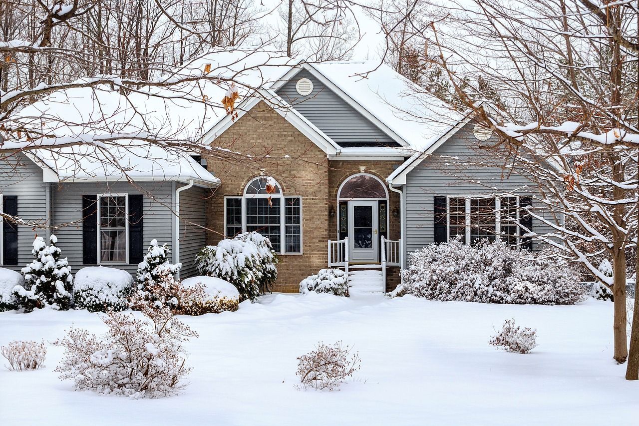 Snow falling on a home representing winter plumbing preparation in Central Ohio.
