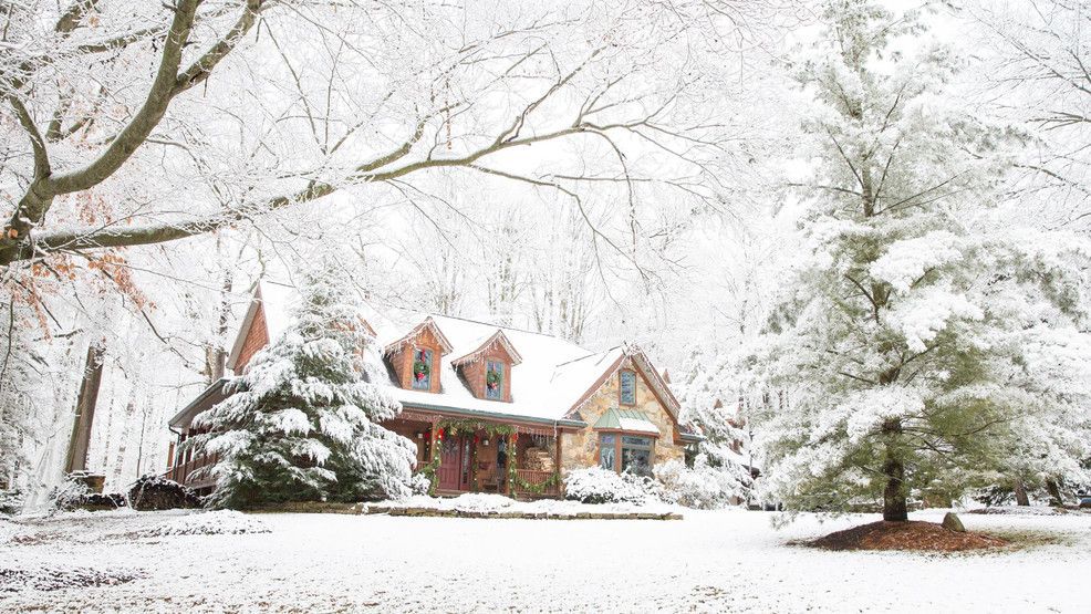 Snow falling on a home with exposed outdoor faucets and a covered hose, representing winter plumbing preparation in Central Ohio.