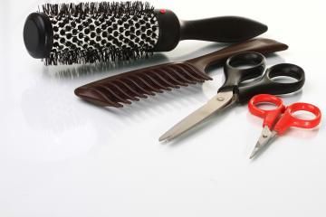 Hairbrushes, comb, and scissors arranged on a white surface