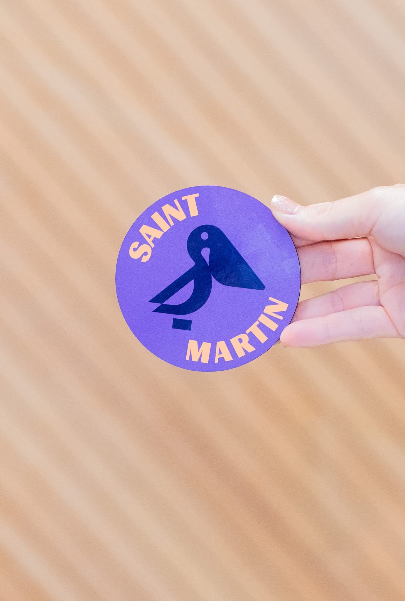 Une personne tient un autocollant violet qui dit saint martin