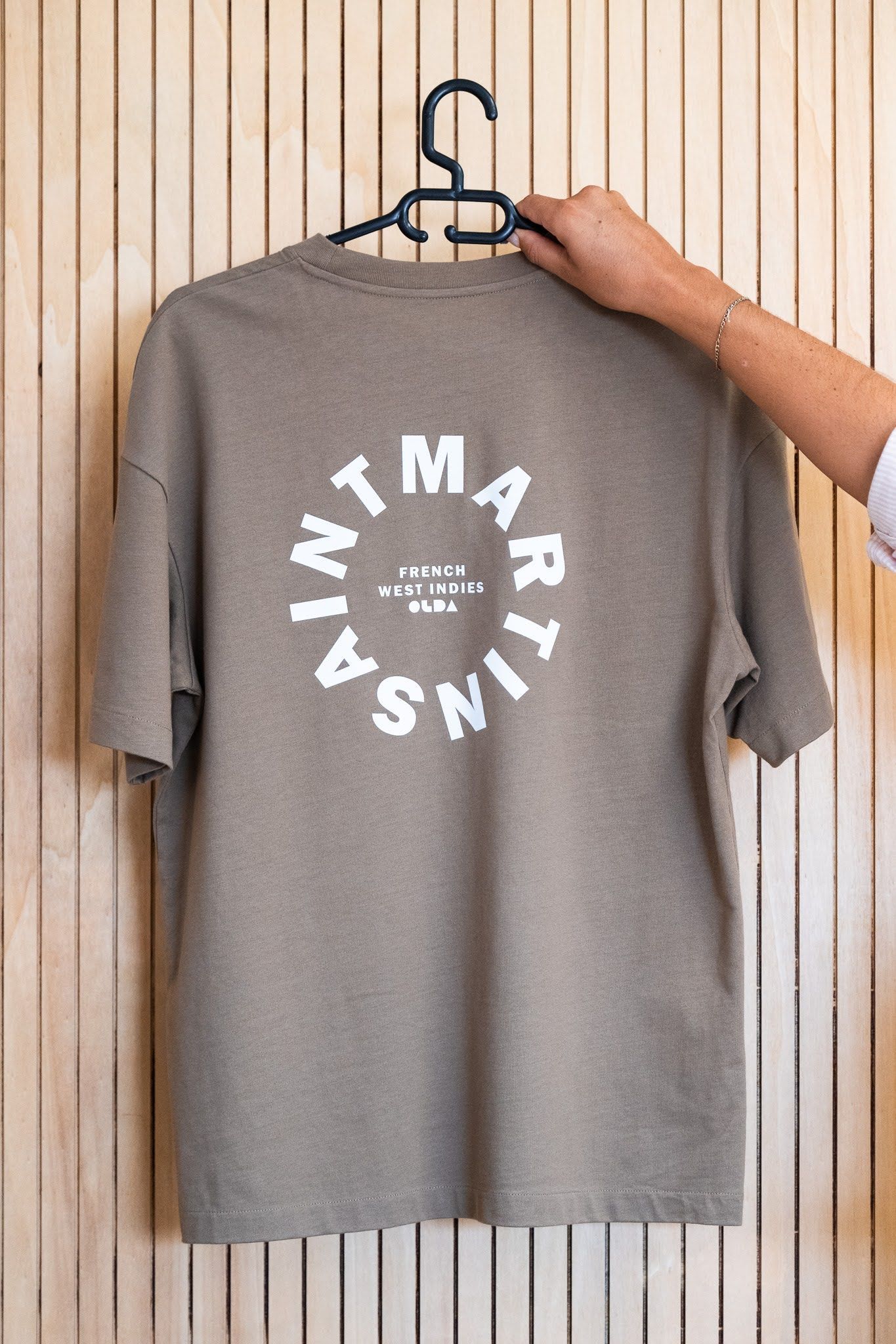 Une personne tient un t-shirt accroché à un cintre.