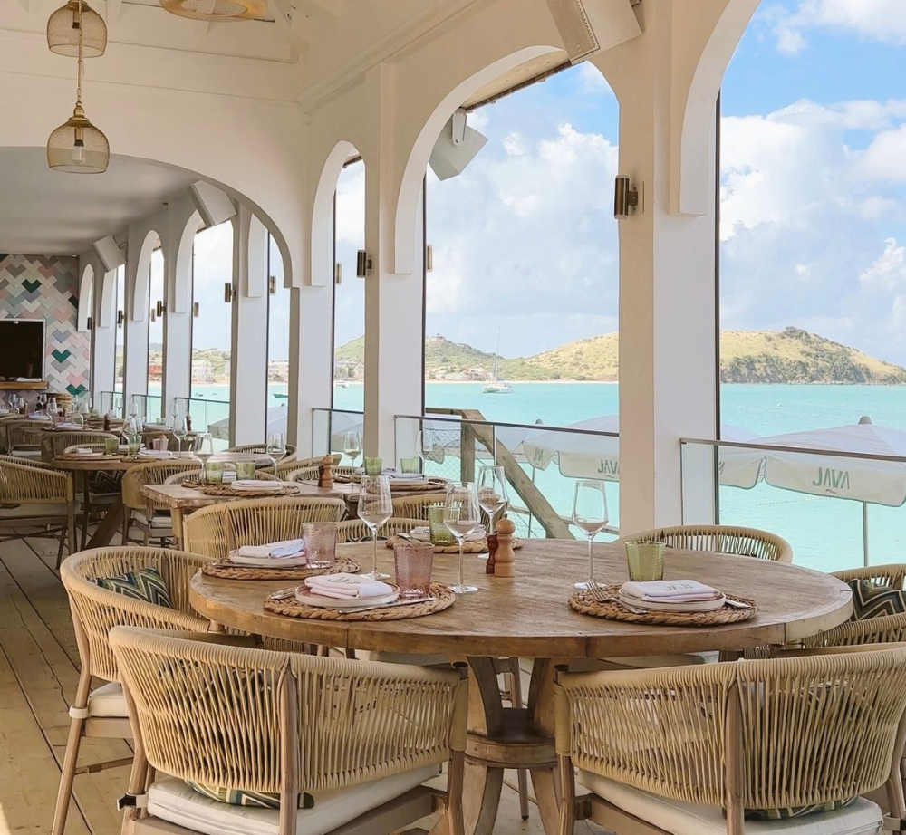 A restaurant with tables and chairs overlooking the ocean