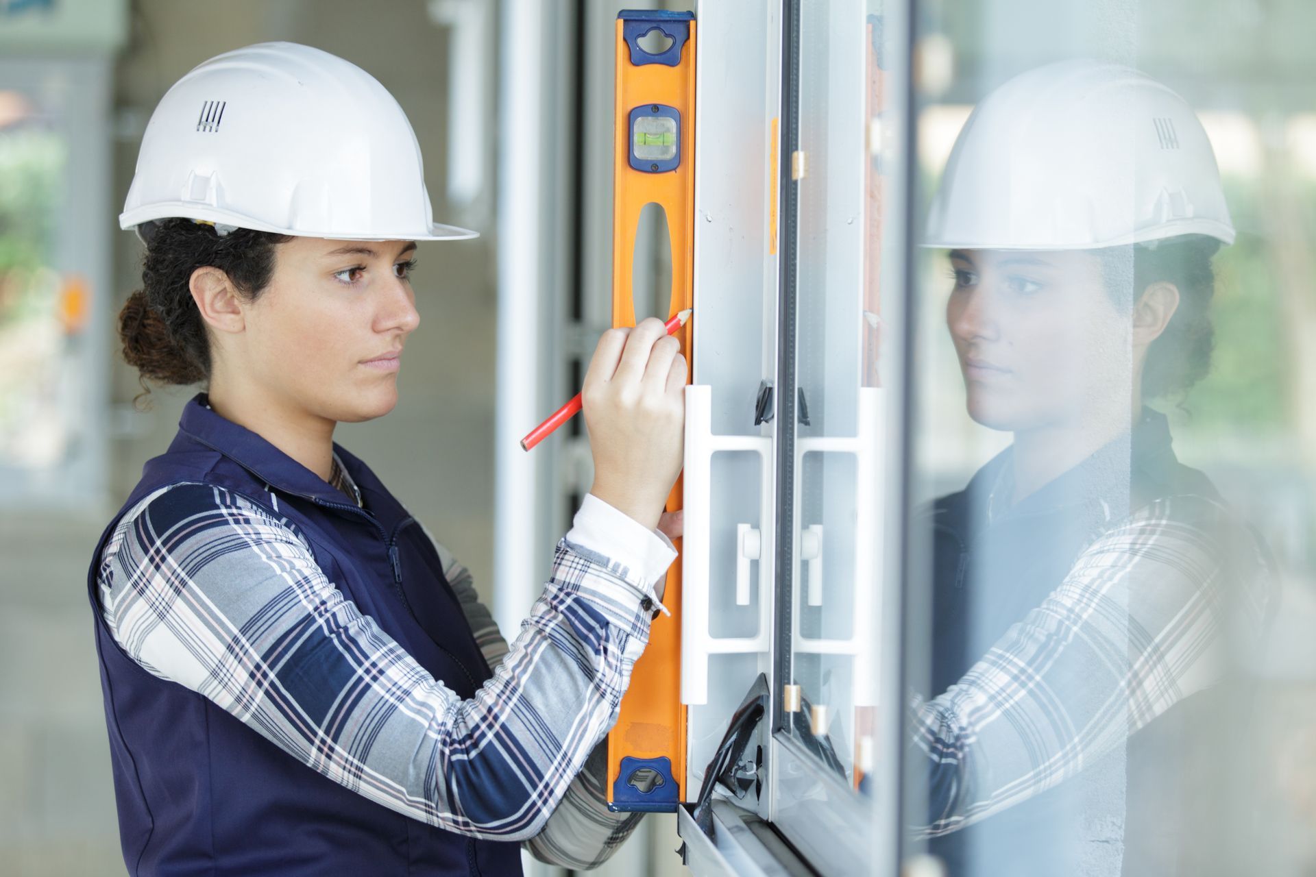A woman is using a level to measure a window.