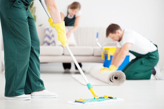 Three people cleaning a light-filled room.