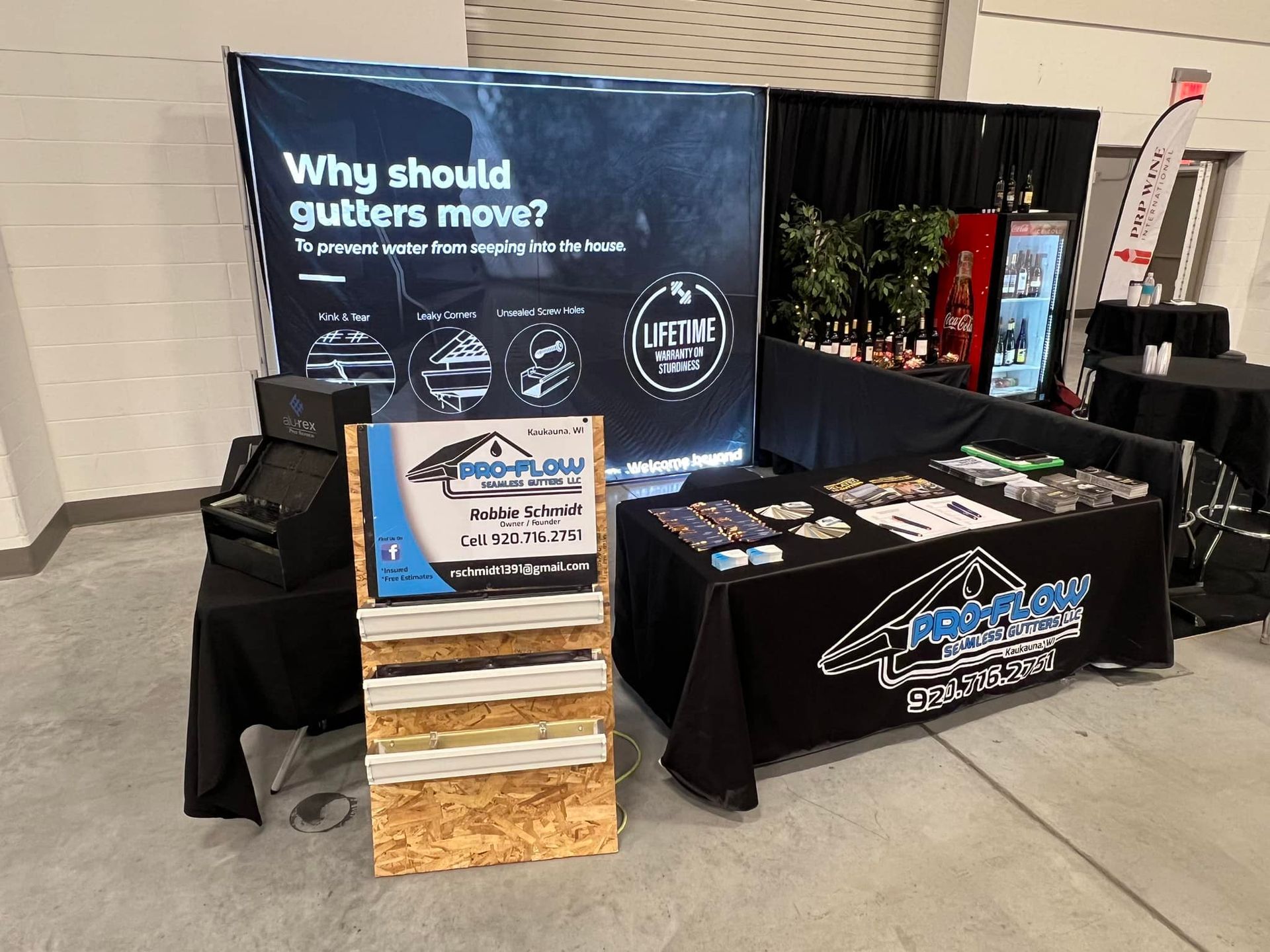 Trade show booth for Pro-Flow Gutters featuring a display board, information stand, and black tablecloth with brand logo.