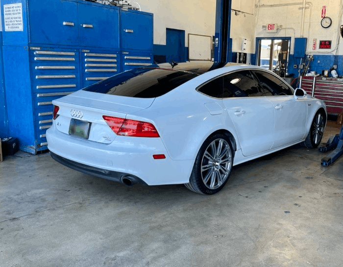Blue Audi sports coupe parked outdoors on a sunny street, front three-quarter view