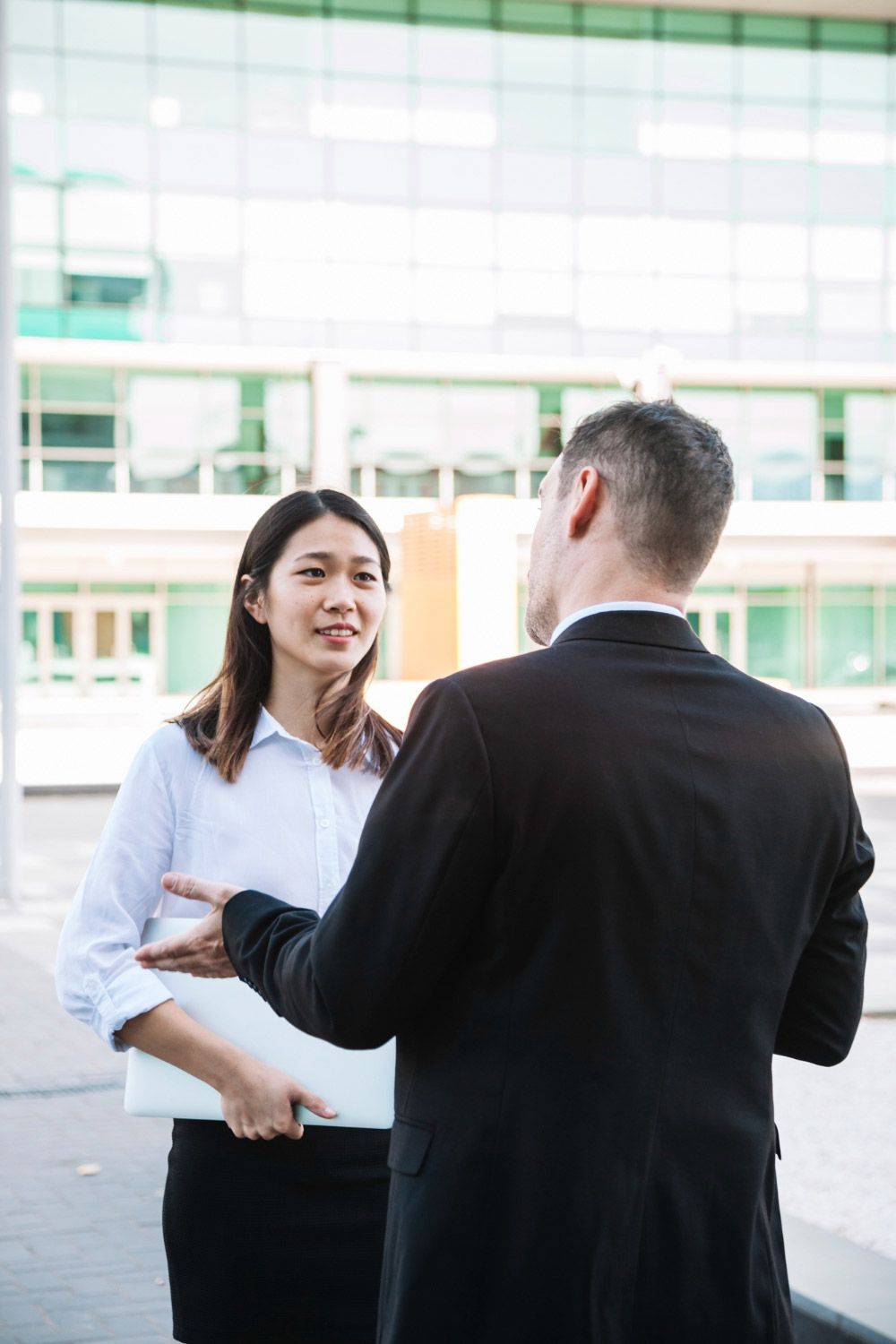 A man and a woman are talking to each other in front of a building.