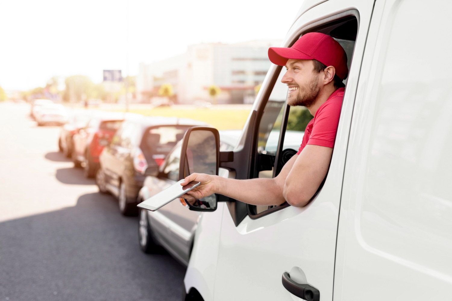 A delivery man is sitting in a white van holding a piece of paper.