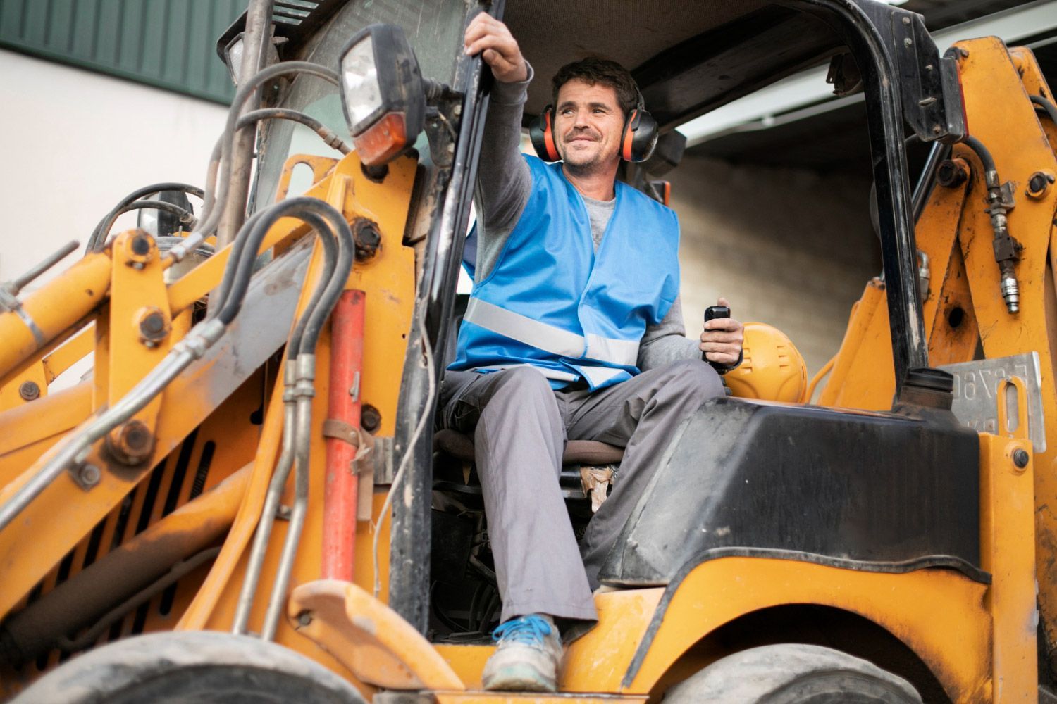 A man is sitting in the driver 's seat of a construction vehicle.