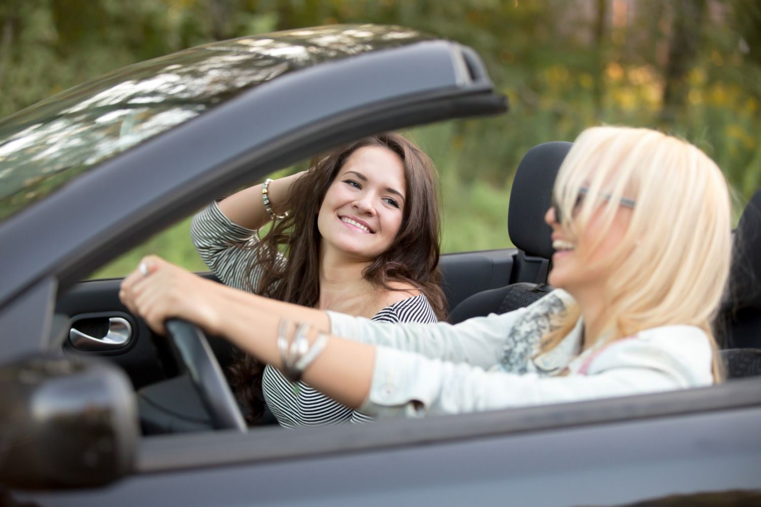 Two women are sitting in a convertible car.