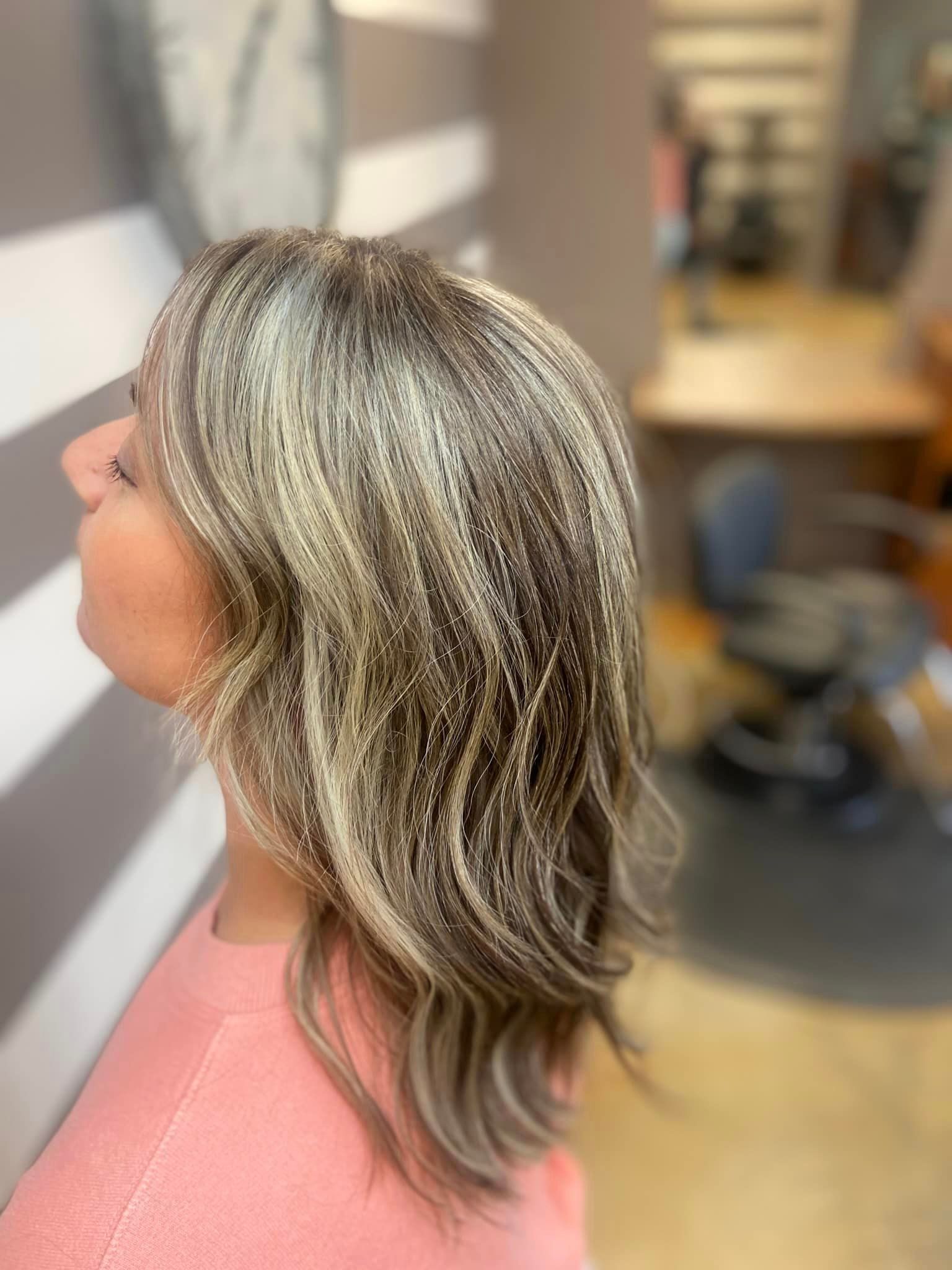 A woman with blonde hair is sitting in a chair in a salon.