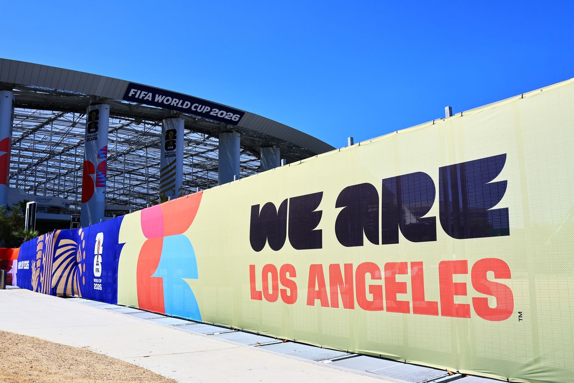 Large mural reading “WE ARE LOS ANGELES” outside a stadium under a blue sky