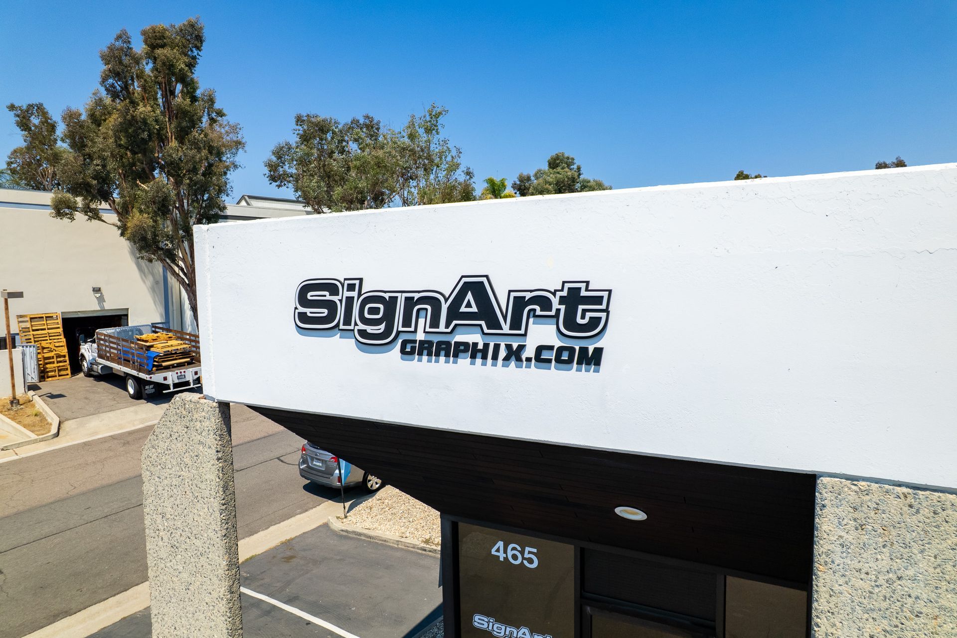 Sign Art business exterior with logo on a white building. A truck is parked nearby.