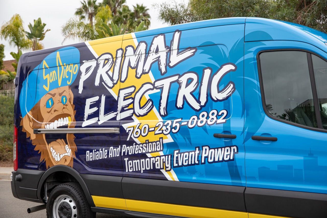 A professionally wrapped blue van featuring the Primal Electric logo and a cartoon primate 