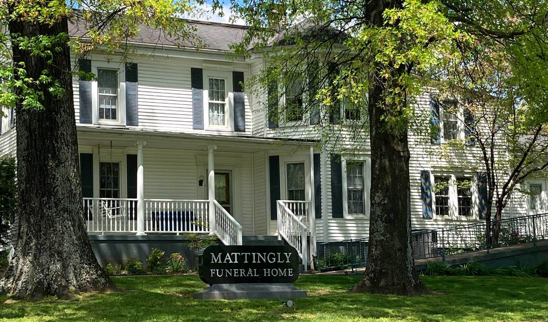 The front door of a house with a porch and plants in front of it.