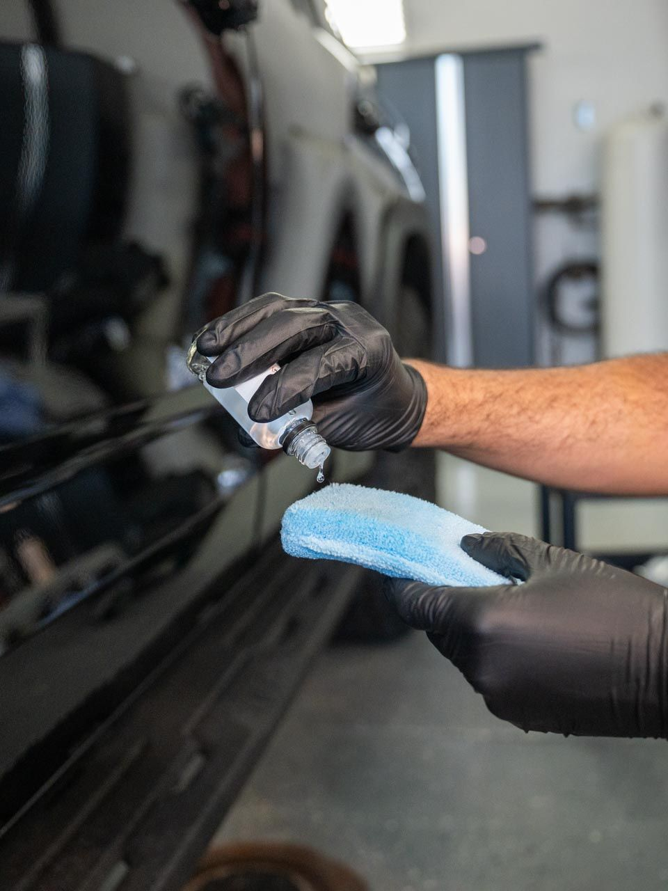 A person is cleaning a blue car with an orange towel