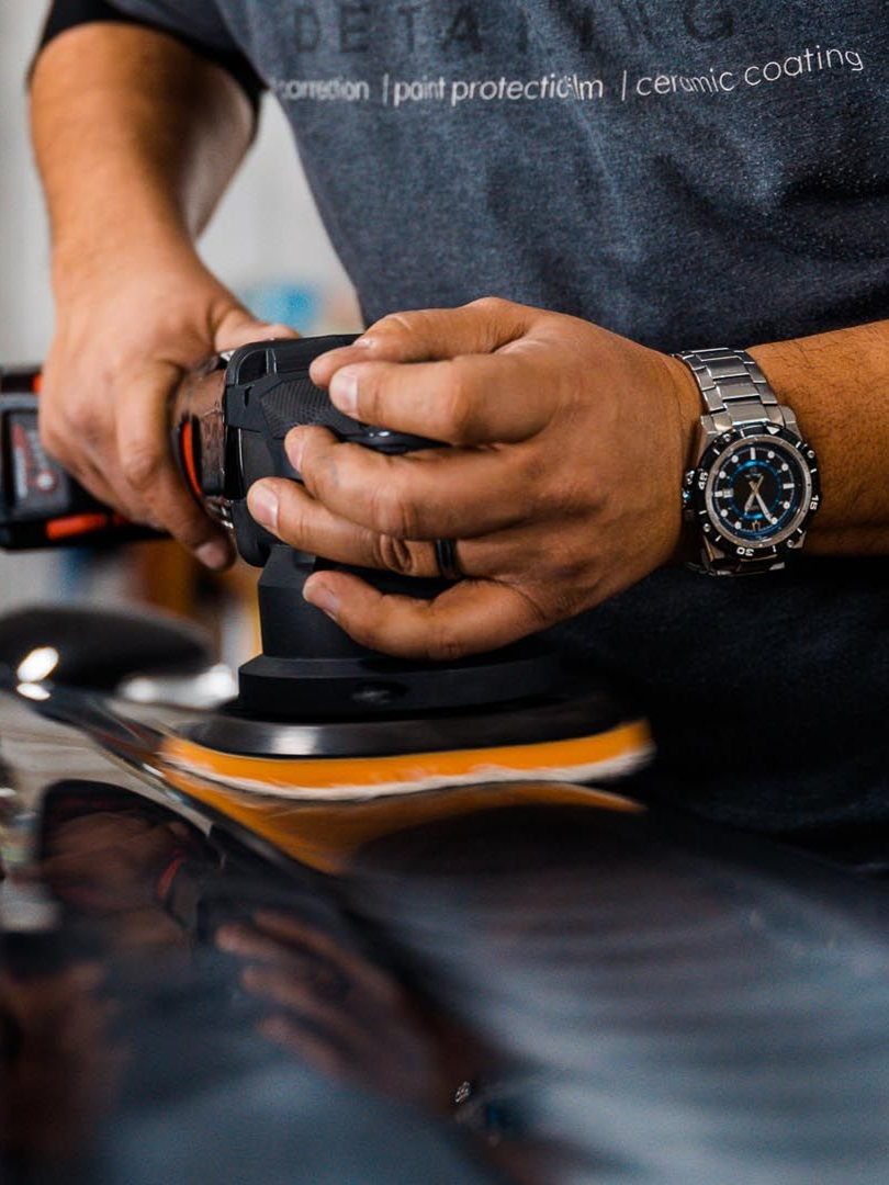 Person polishing a car with a power buffer.