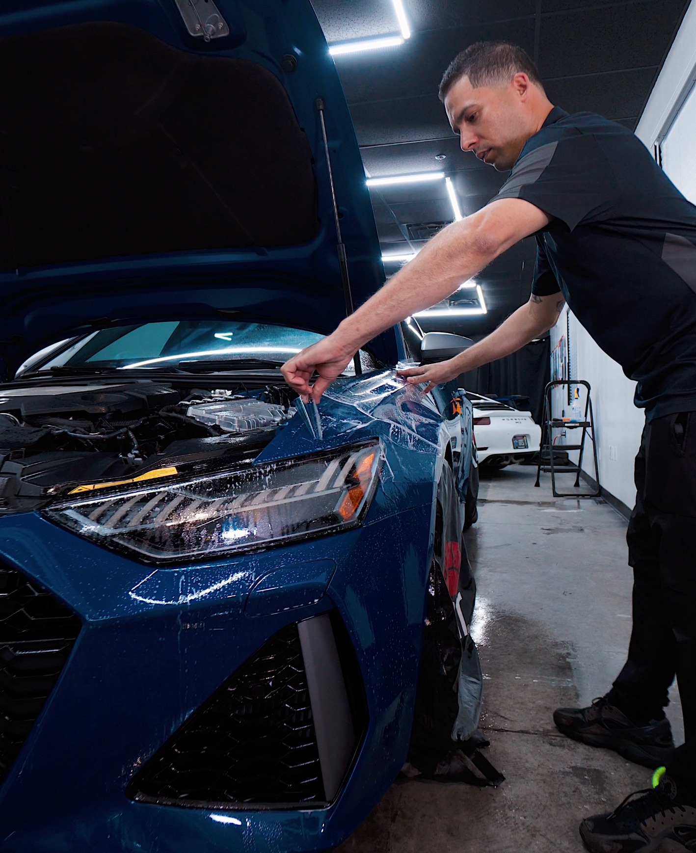 A silver car is being washed with soap and water