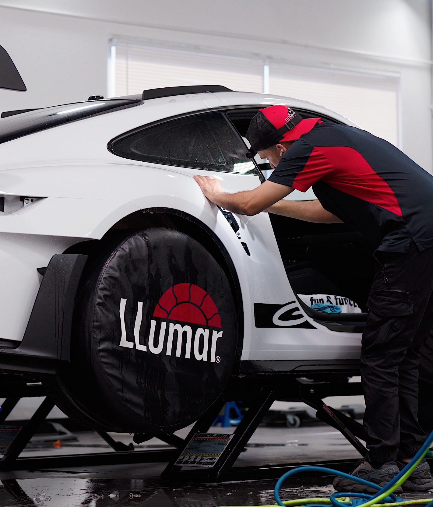 A person is cleaning a blue car with an orange towel