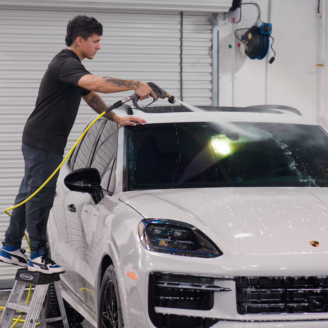 A person is cleaning a blue car with an orange towel