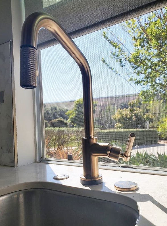 A kitchen sink with a faucet and a window in the background