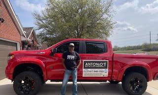 A man is standing in front of a red truck.