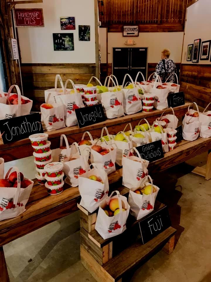 A bunch of bags of apples are sitting on a wooden table.