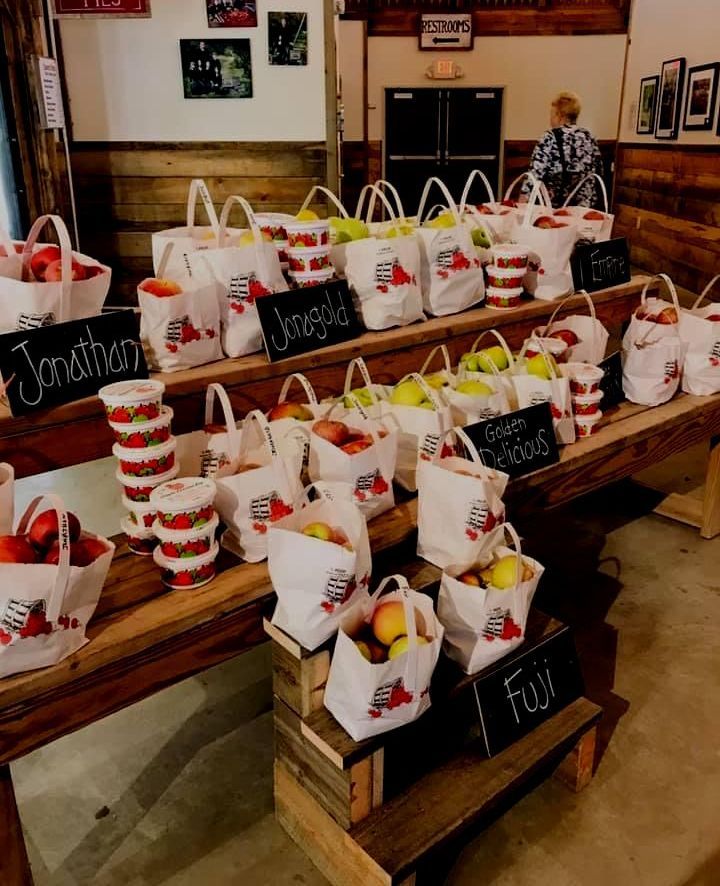 A table full of bags of fruit and a sign that says jonathan