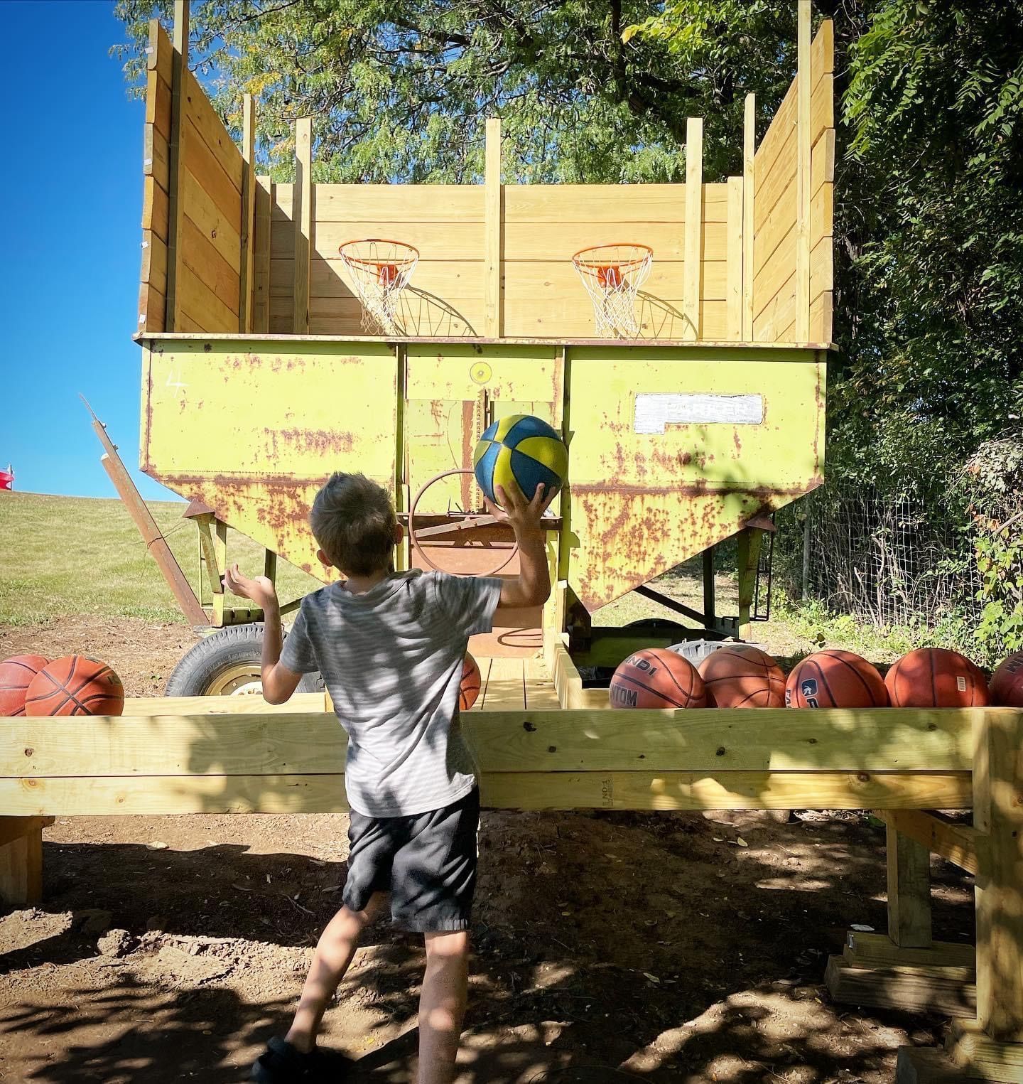 A young boy is holding a ball in front of a yellow trailer