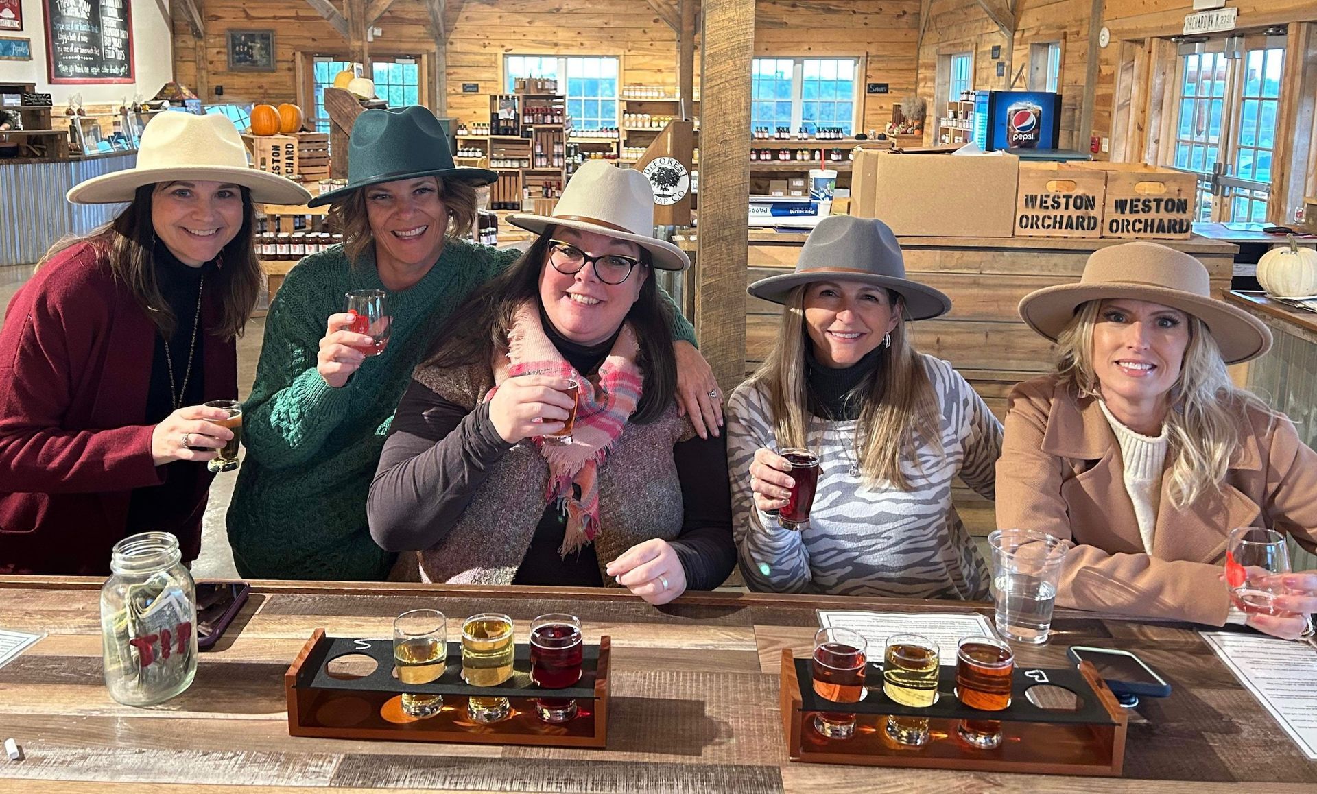 A group of women are sitting at a table holding drinks.