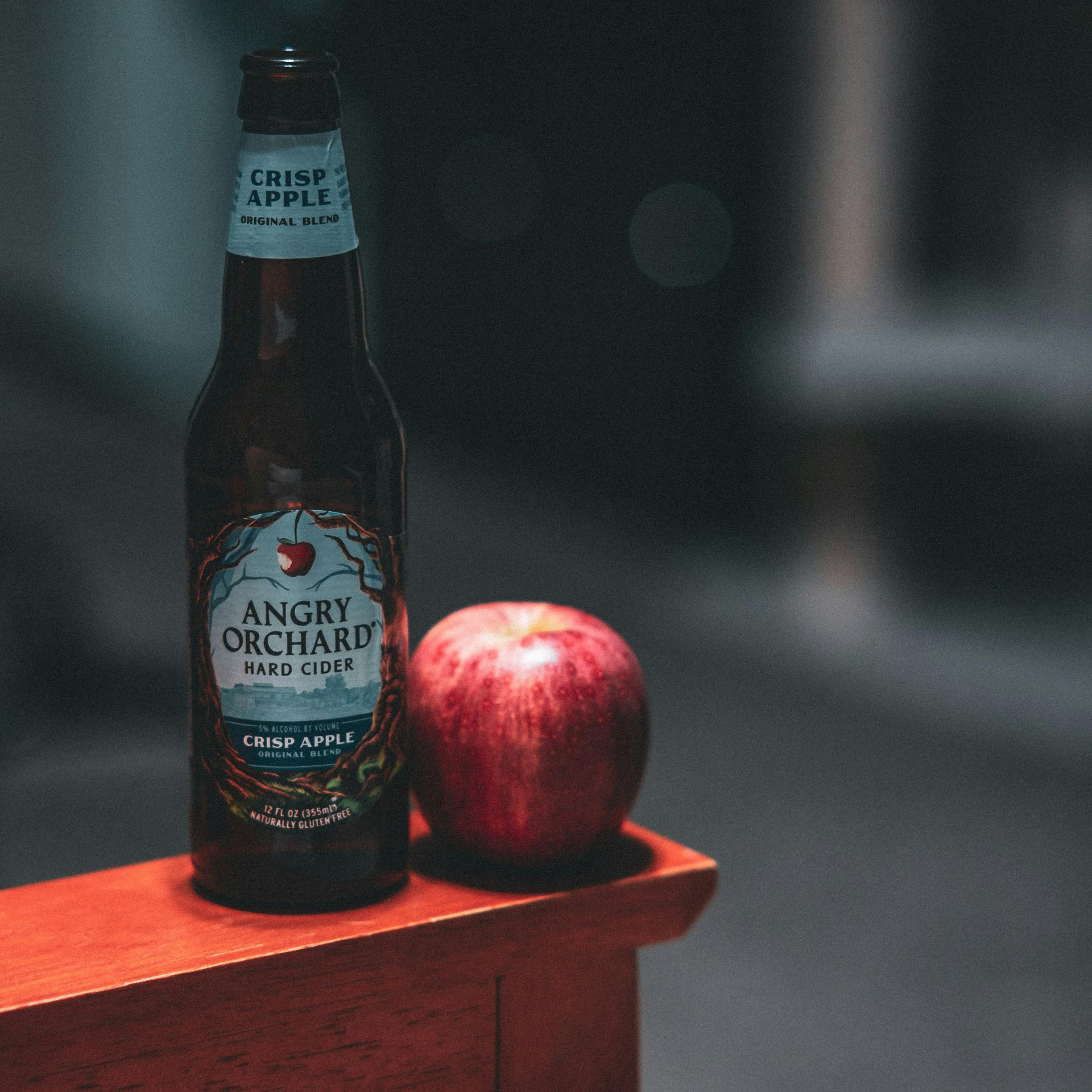 A bottle of angry orchard next to an apple
