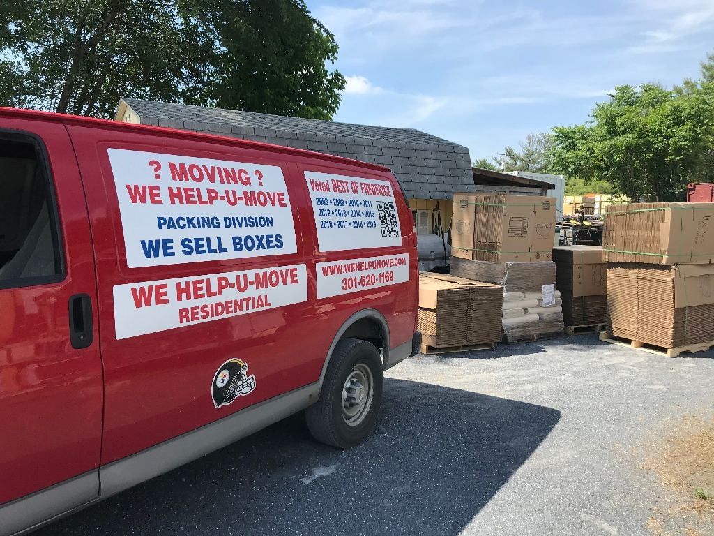 Red van with moving service advertisement; boxes stacked nearby.