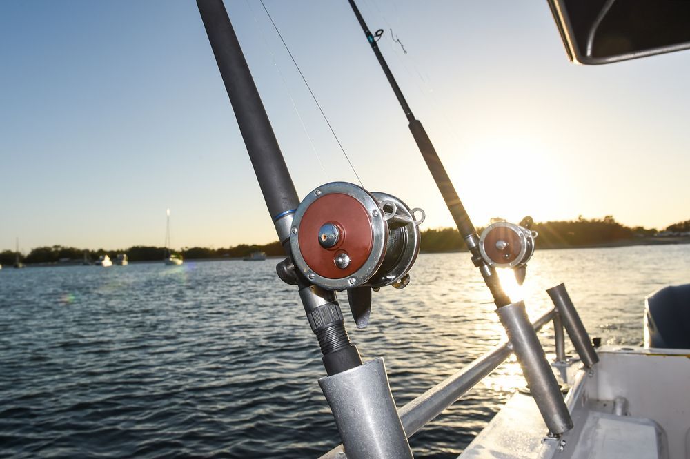 Two fishing rods are sitting on the side of a boat in the water.