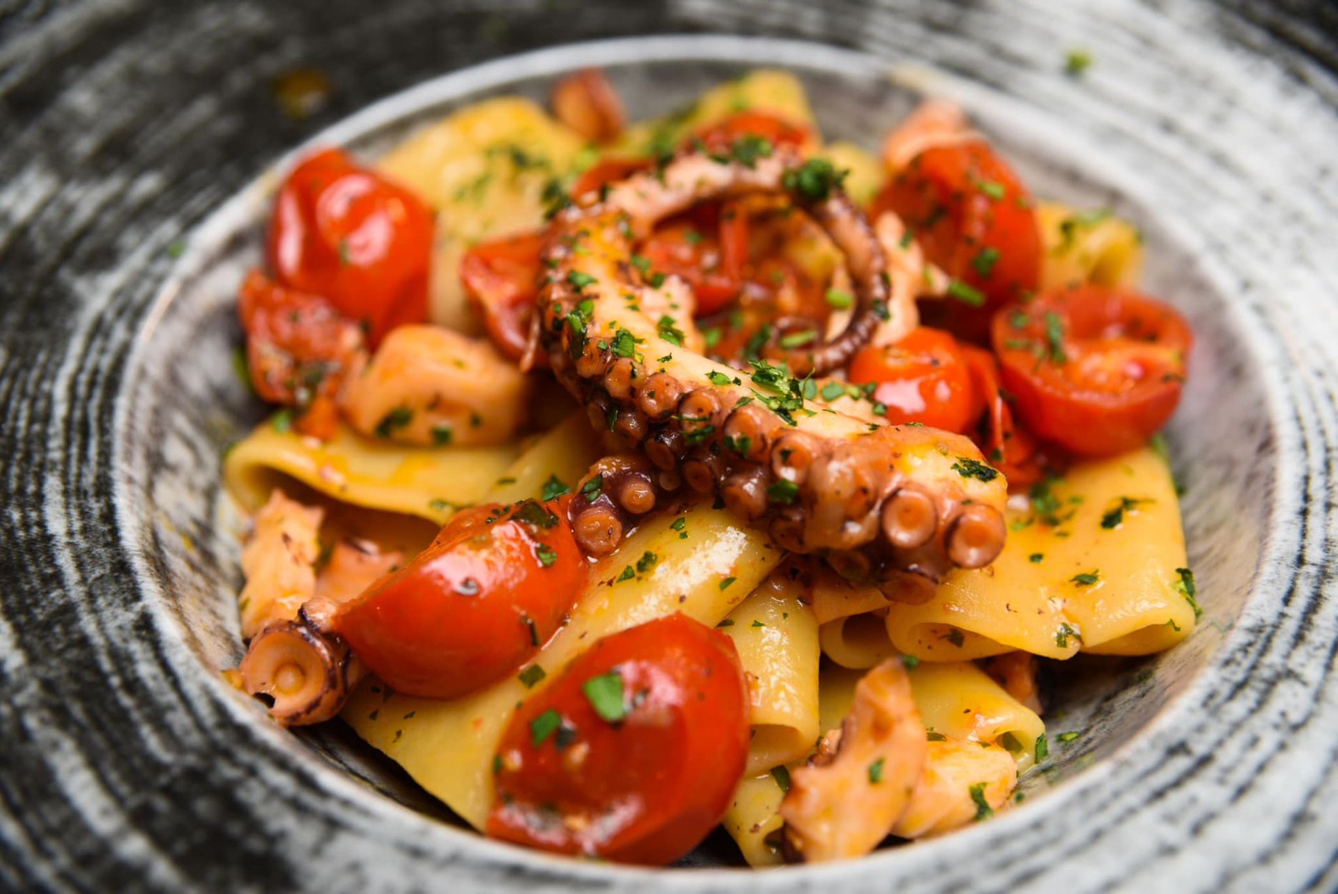 Piatto di pasta con tentacoli di polpo e pomodorini.