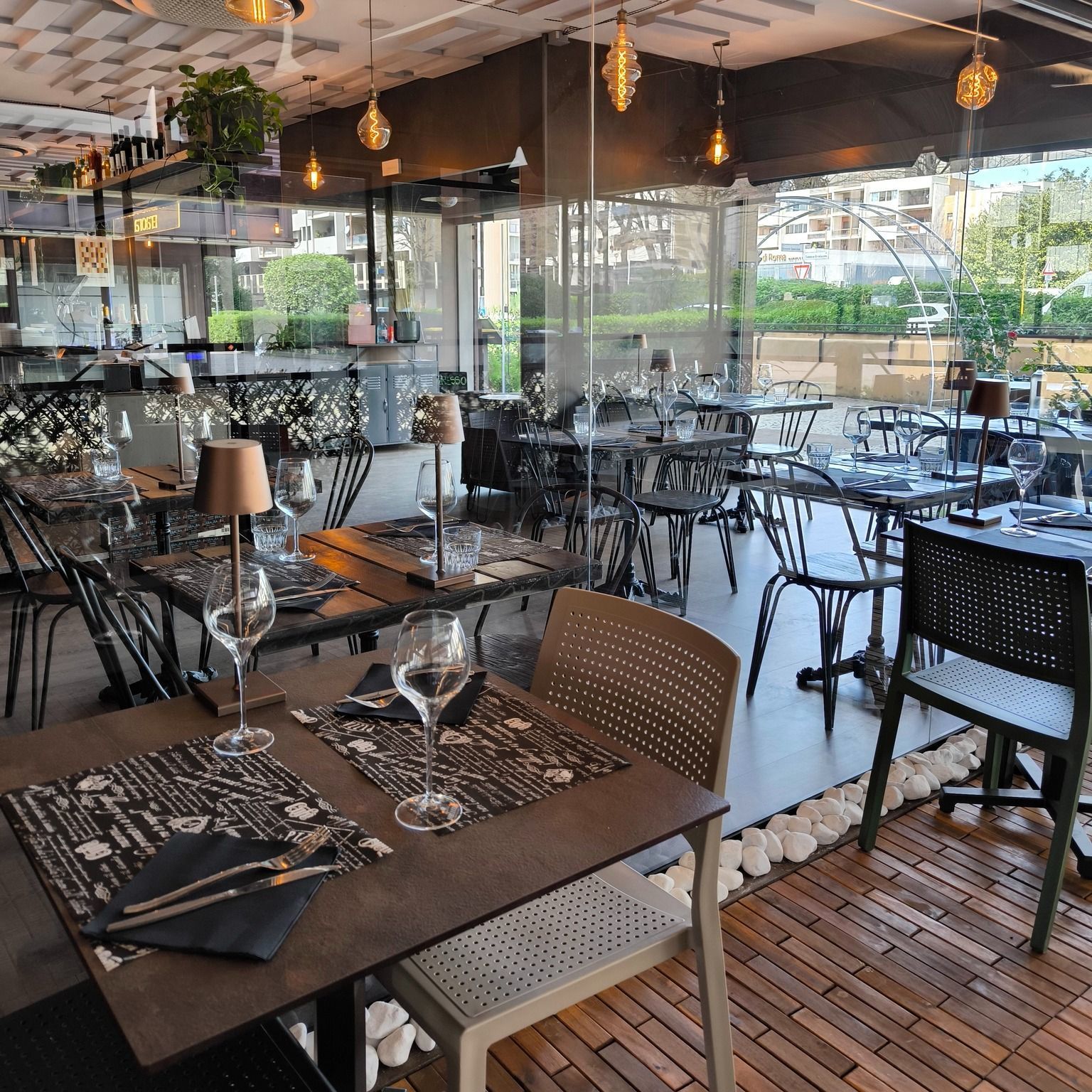 Interno del ristorante con tavoli apparecchiati per cenare e finestre che si affacciano sul verde.