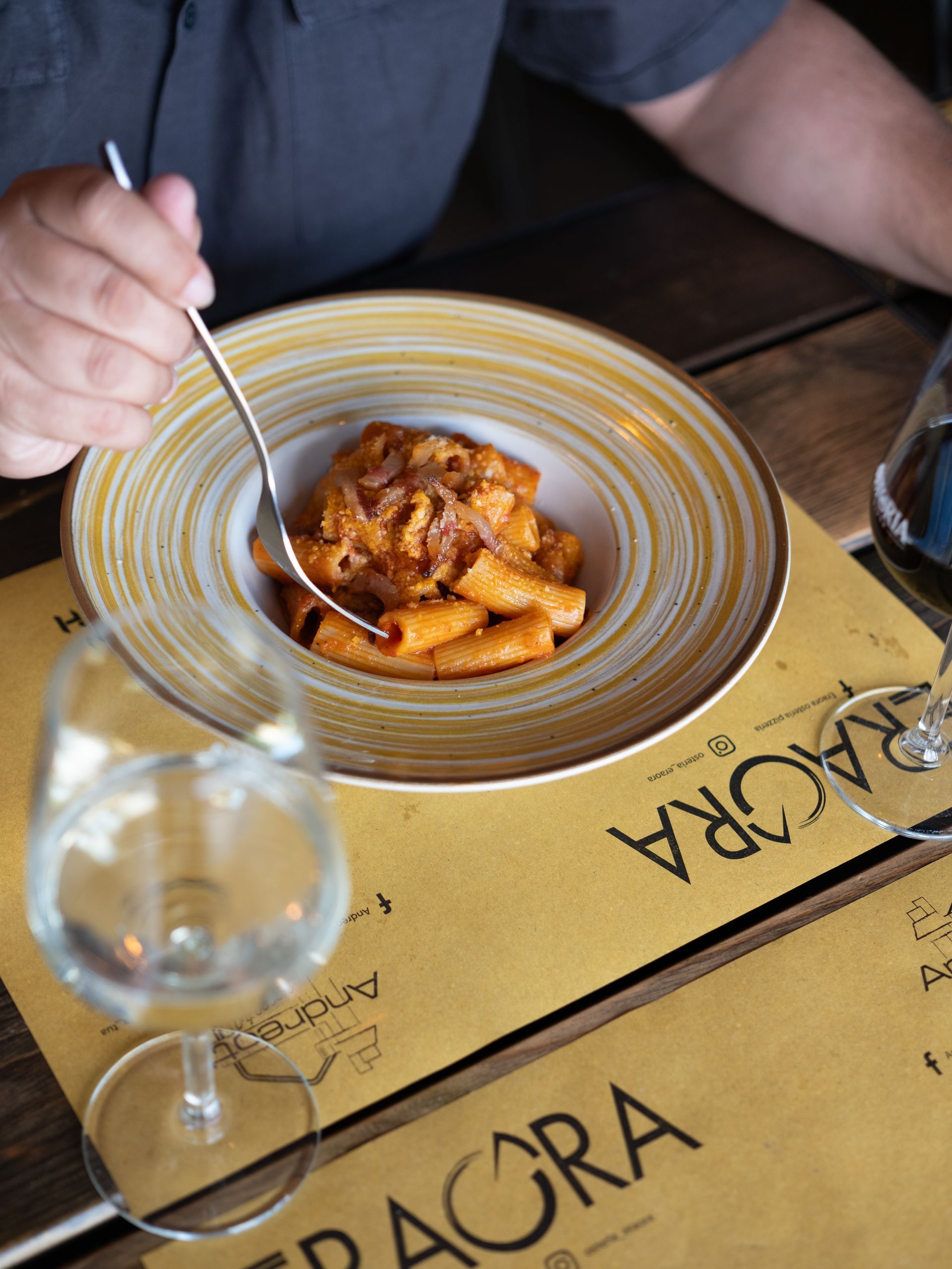 Persona che mangia un piatto di pasta con sugo rosso in un ristorante.