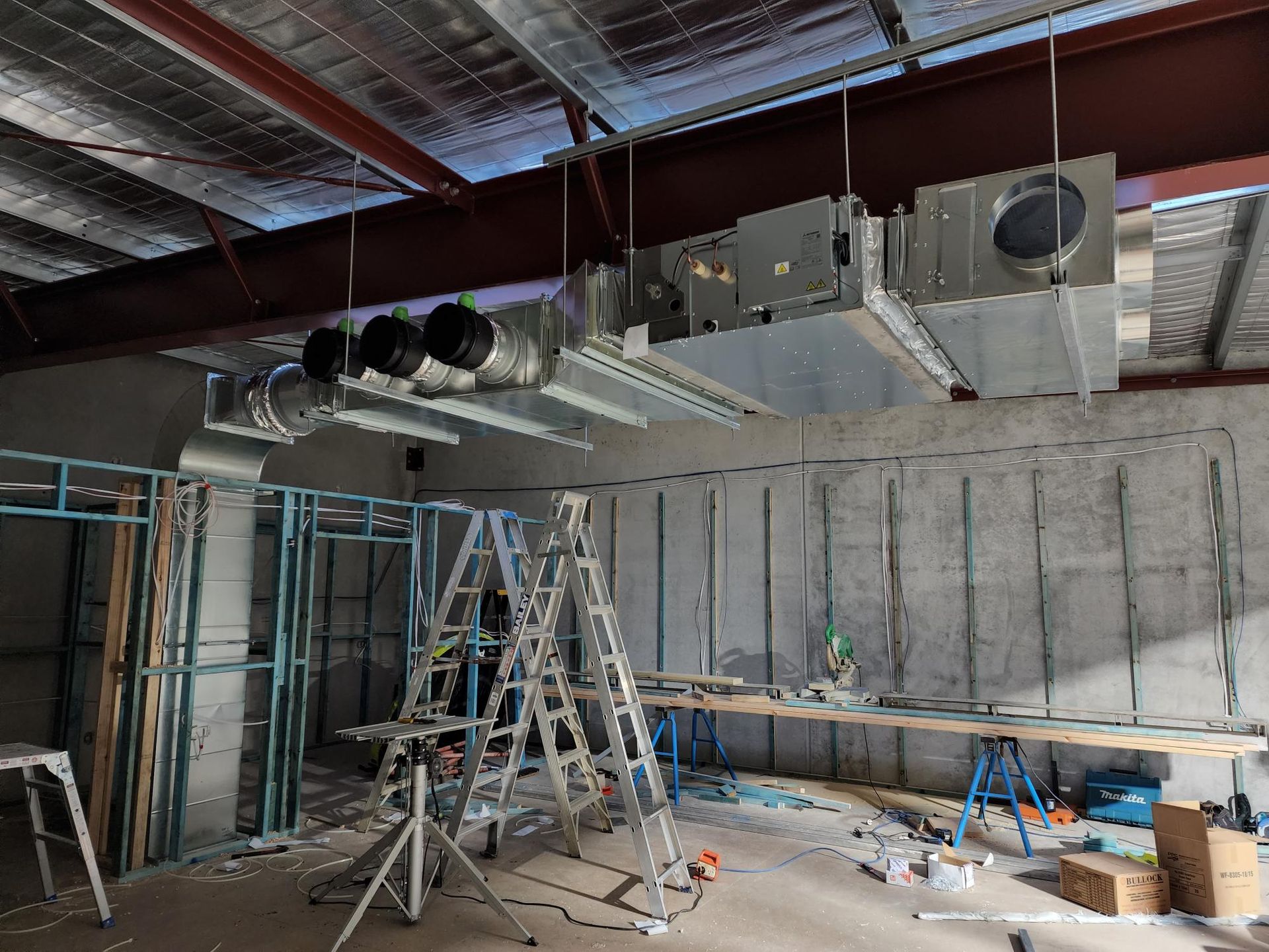 Ducted Air Conditioning installation in a construction site in Nowra. Metal framing and concrete walls are visible.