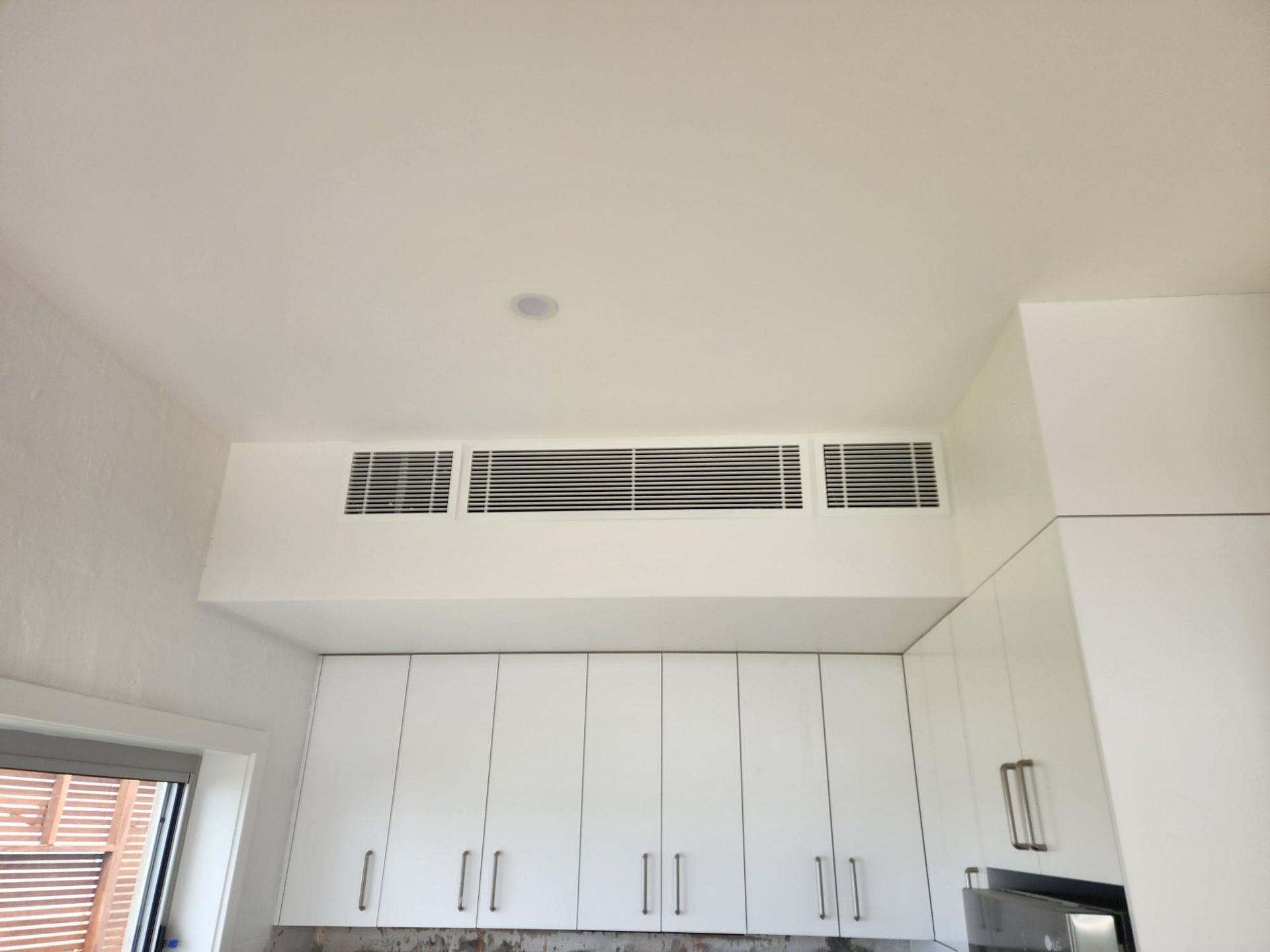 Ducted Air Conditioning with cabinets, soffit with vents, and a single ceiling light.