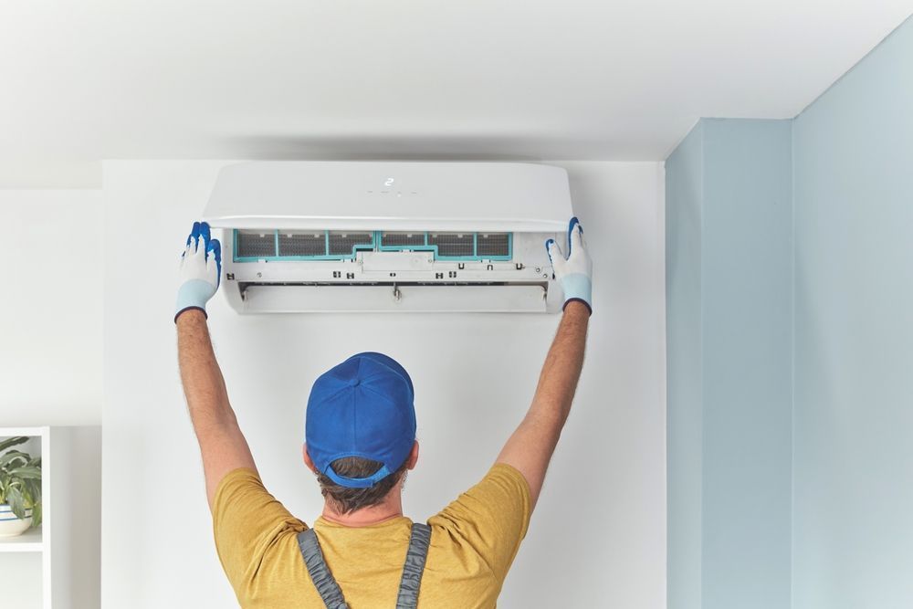 A man is installing an air conditioner in a room.