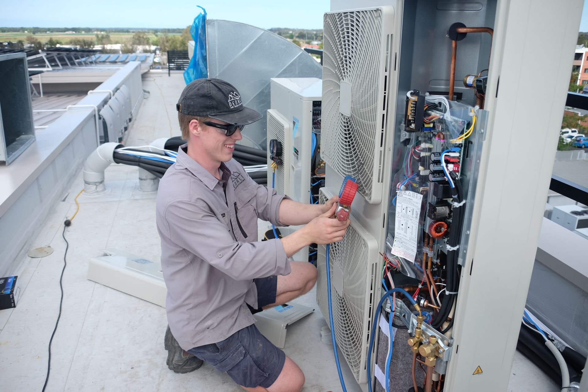 A technician repairs rooftop HVAC equipment