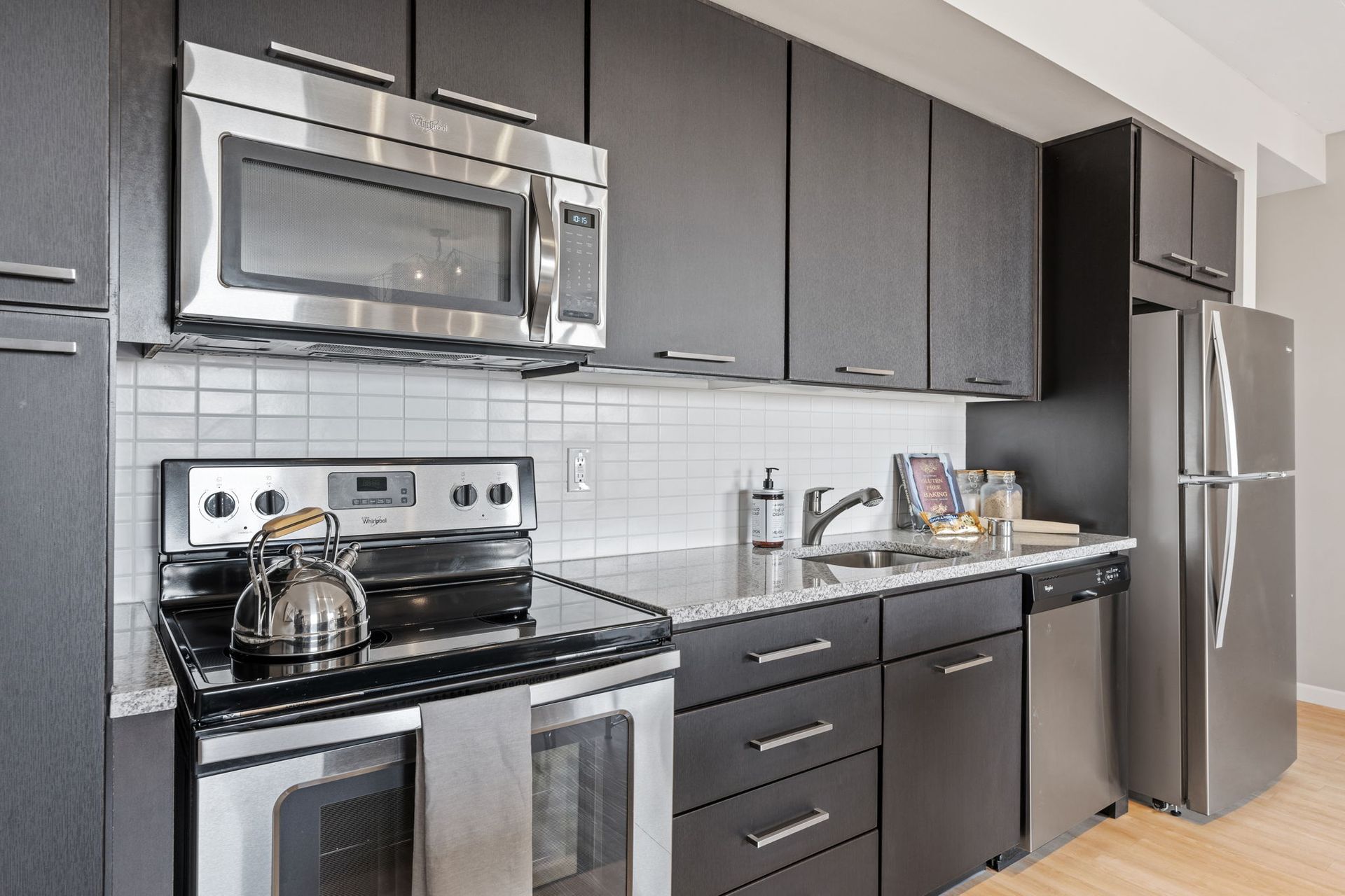 Modern kitchen with black cabinets, stainless steel appliances, and granite countertops.
