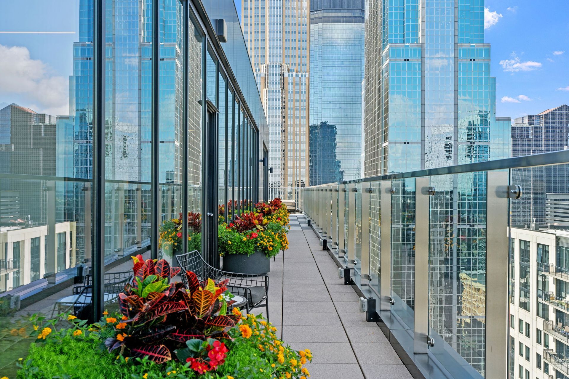 Rooftop patio with flower boxes, overlooking cityscape of tall glass buildings.