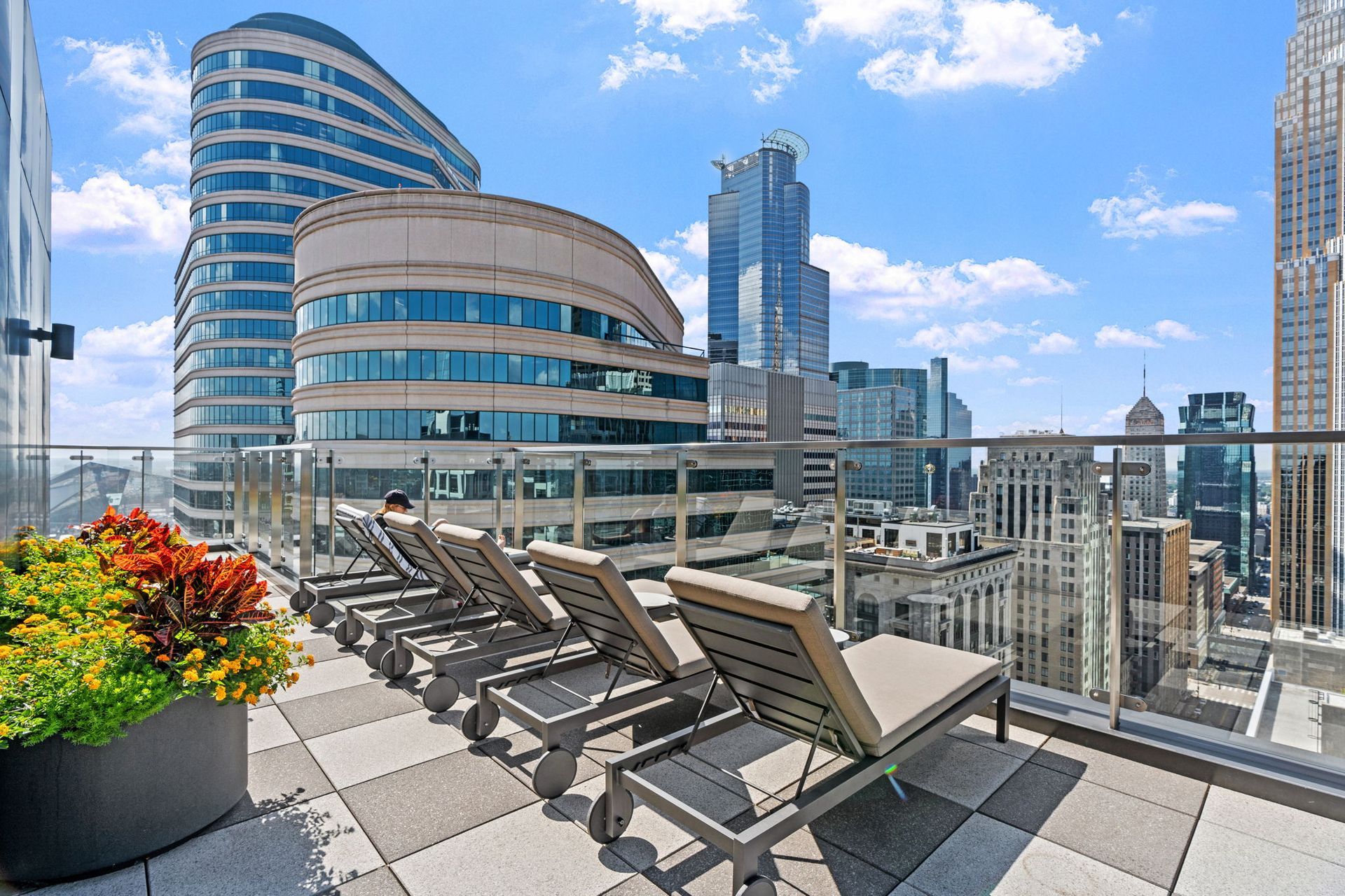 There are a lot of lounge chairs on the roof of a building.
