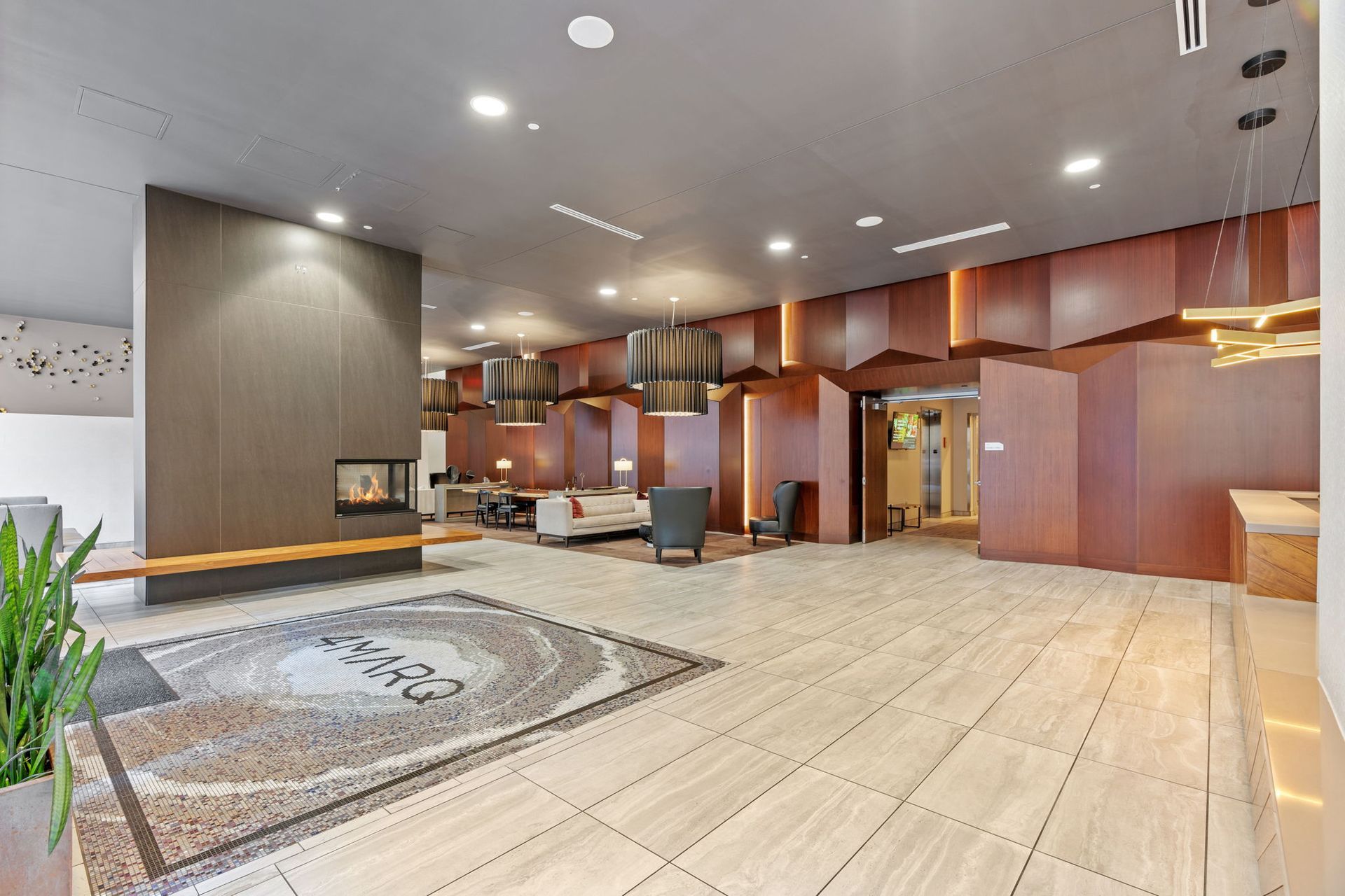 Modern lobby with fireplace, seating area, decorative rug, and wood paneling.